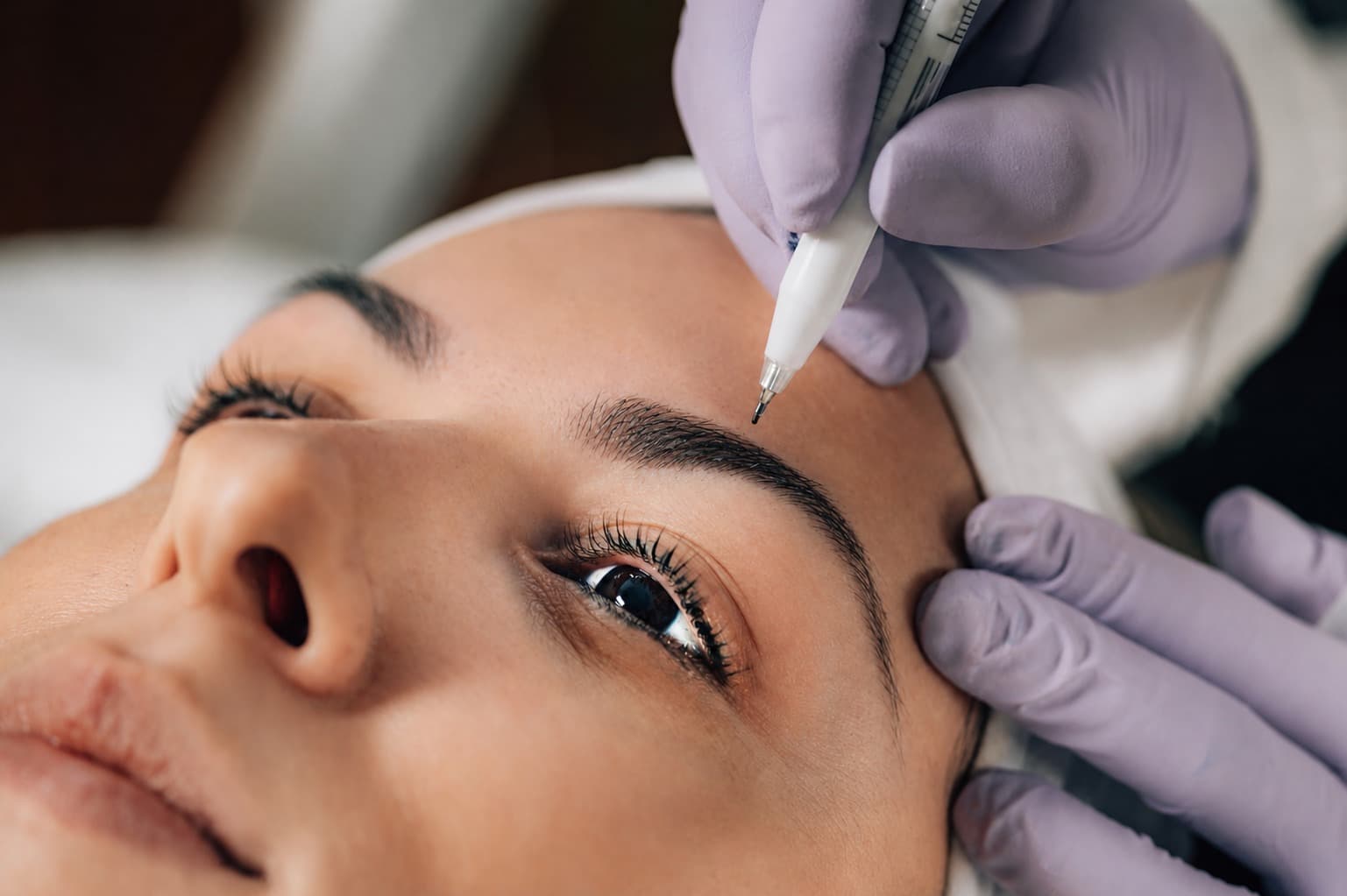 Especialista de micropigmentación trabajando sobre las cejas de una clienta
